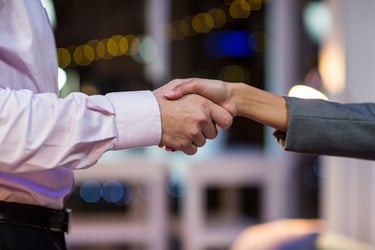 Close-up of businesspeople shaking hands in office at night